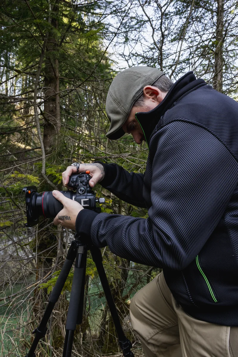 René beim Fotografieren mit Kamera und Stativ im Wald